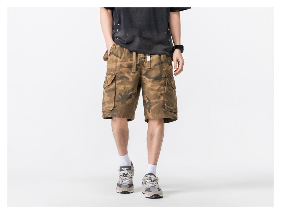 Front view of a model wearing tan camouflage cargo shorts with a drawstring waist and large flap pockets.