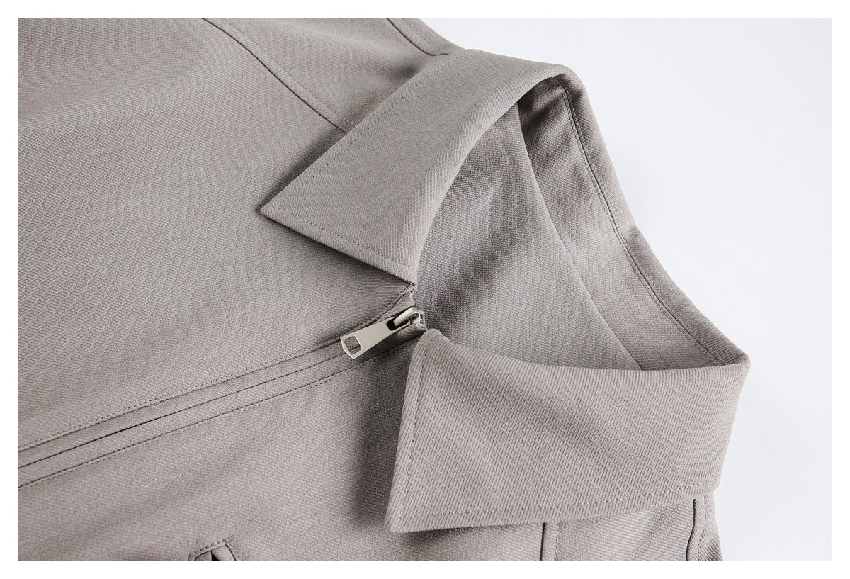 Close-up of a taupe jacket collar, lapel, and short metal zipper.