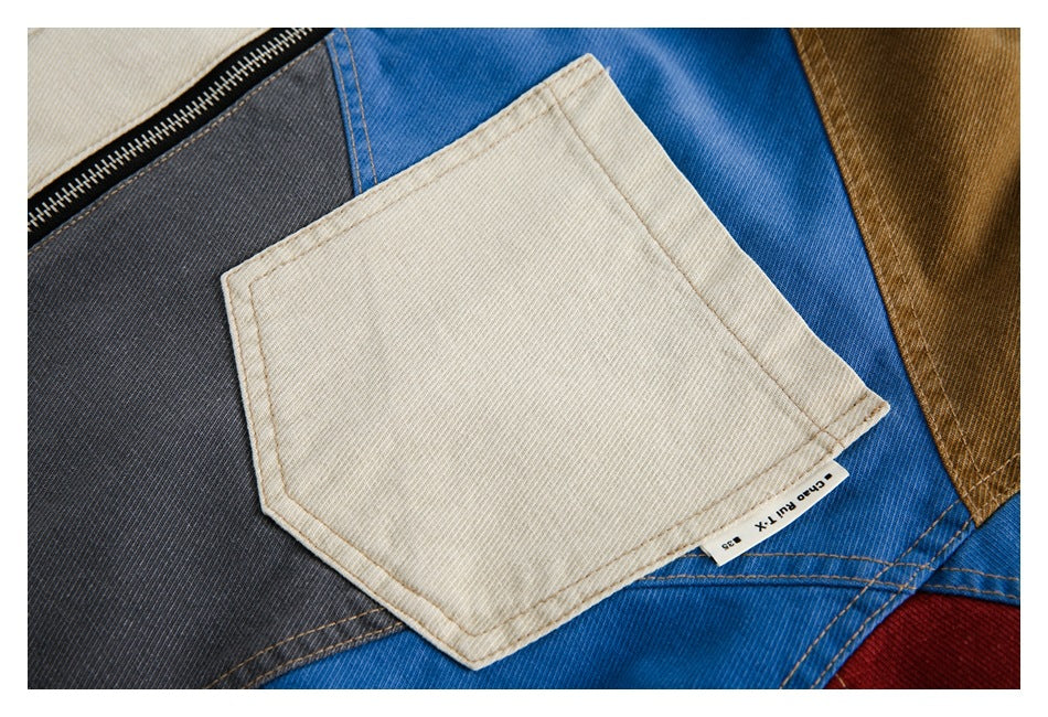 Close-up of a cream chest pocket against blue, charcoal, and tan jacket panels.
