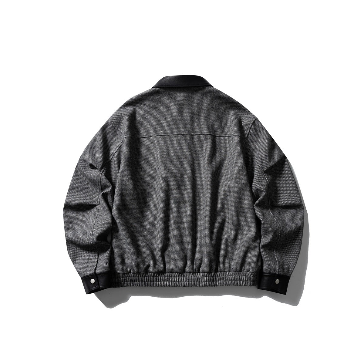 Back view of a charcoal gray patterned jacket with a black collar, gathered hem, and snap-button cuffs.
