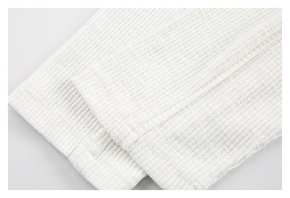 Close-up of a ribbed cuff and stitched edge on the off-white top.
