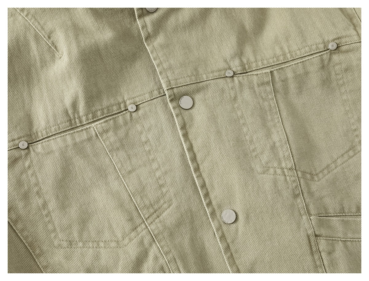 Close-up of a light khaki jacket front showing its snap placket, chest pockets, and small metal buttons.