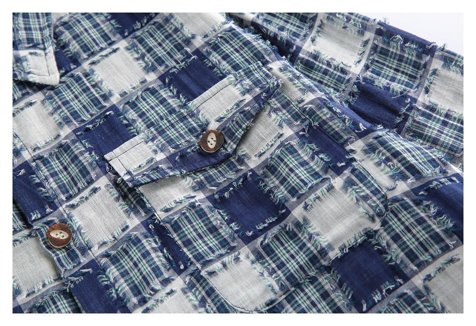 Close-up of a blue, green and white patchwork plaid garment with frayed edges and brown buttons.