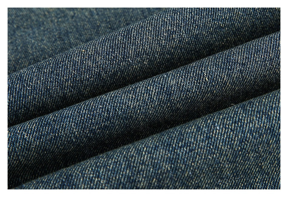 Macro view of dark blue denim fabric with visible diagonal weave and subtle fading.