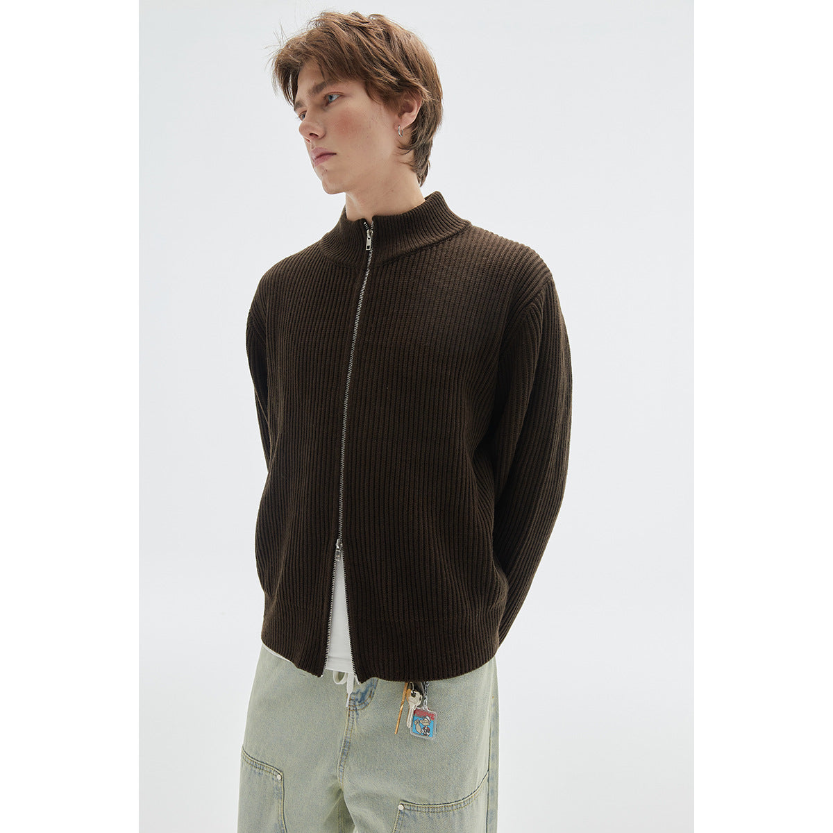 Close view of a model wearing a dark brown ribbed cardigan with a front zipper and high collar.