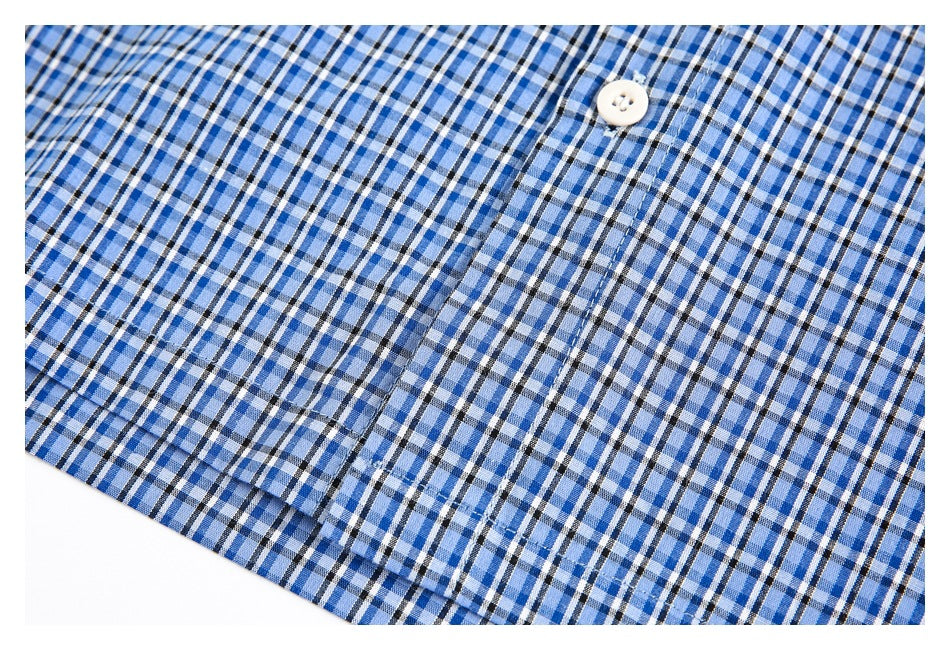 Close-up of blue plaid garment fabric with a white button and stitched placket.