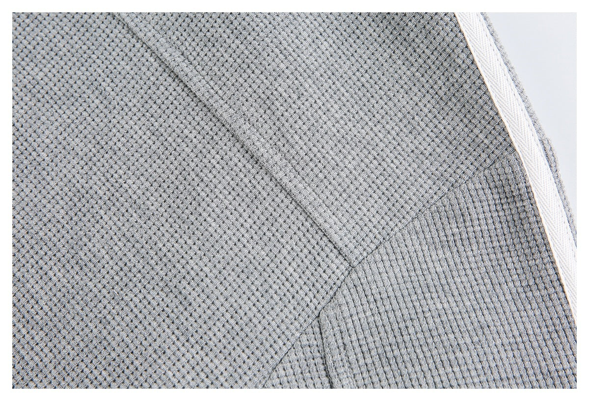 Close-up of a stitched seam and white stripe on light gray textured fabric.