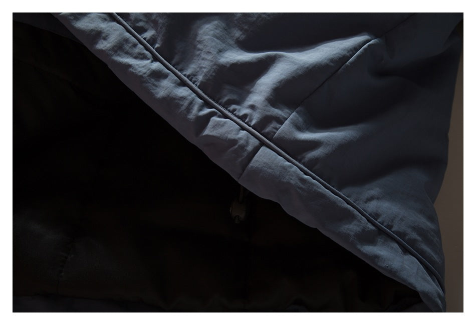 Close-up of a blue-gray jacket edge with narrow piping, draped against a dark background.