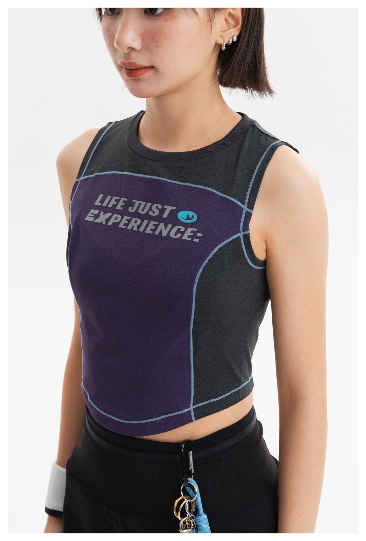 Close-up of a purple and charcoal sleeveless crop top with blue piping and English chest lettering.