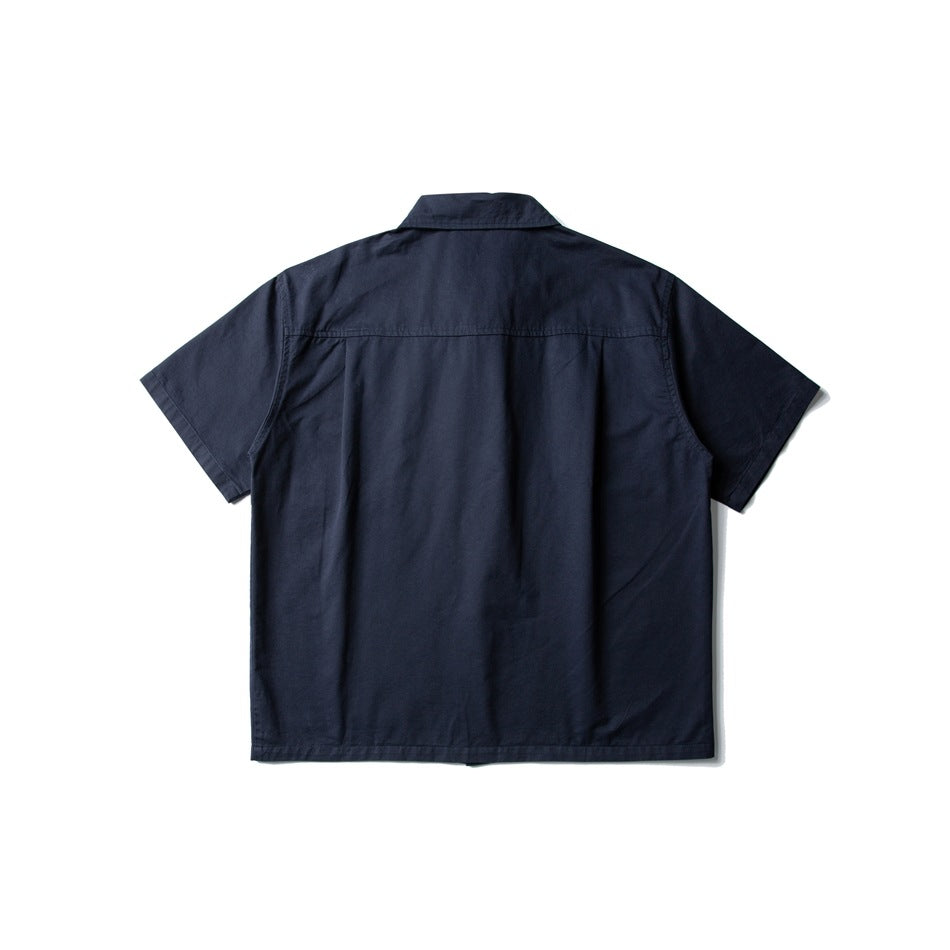 Back view of a navy blue short-sleeve shirt, flat lay, with yoke seam and center pleat