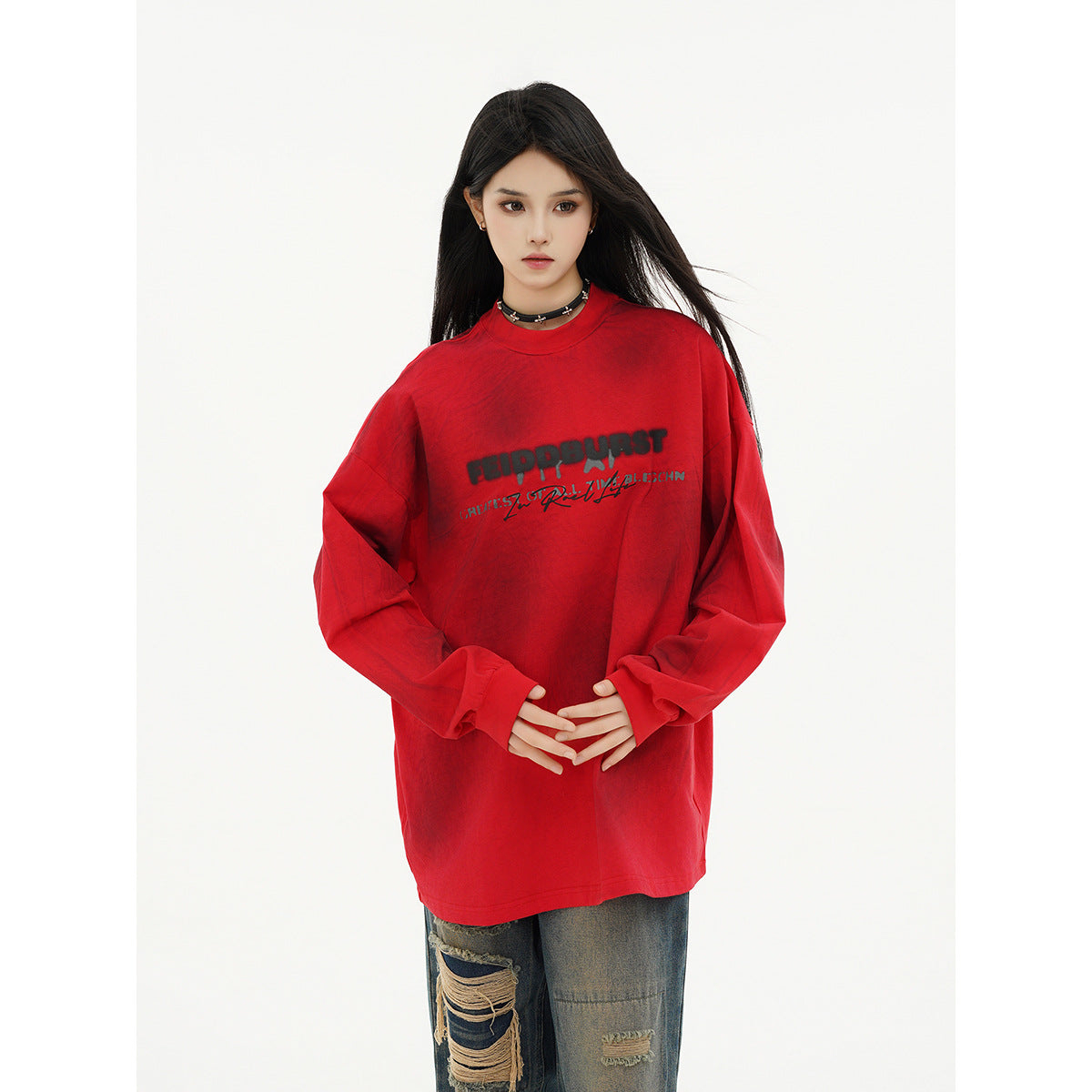 Closer view of a model wearing an oversized red long-sleeve shirt with black chest lettering.