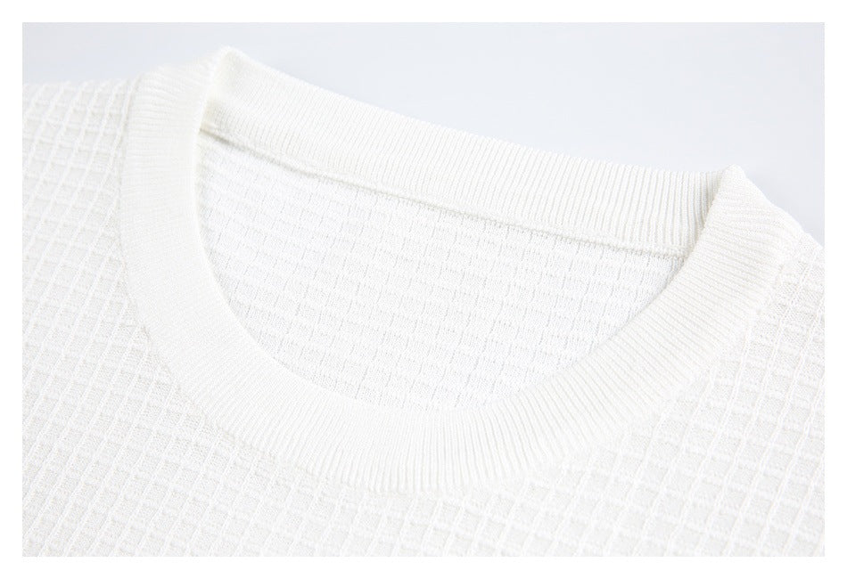 Close-up of a white knit shirt's ribbed crew neck and textured fabric.