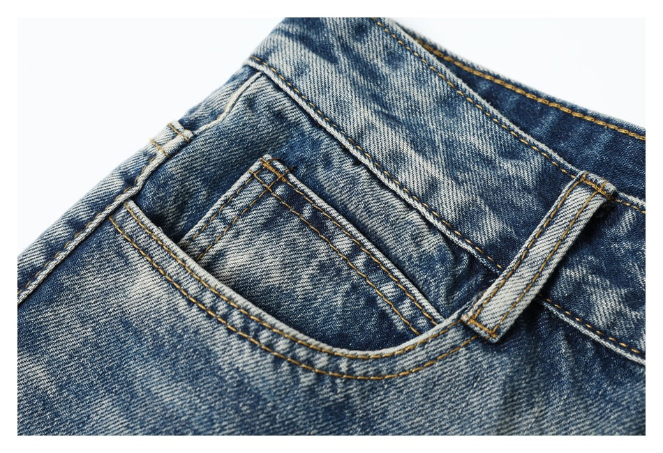 Close-up of the small coin pocket and curved front pocket on blue acid-wash jeans.