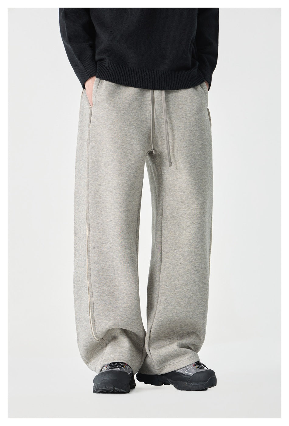 Model wearing light gray wide-leg sweatpants with drawstring waist and black sweater, front view