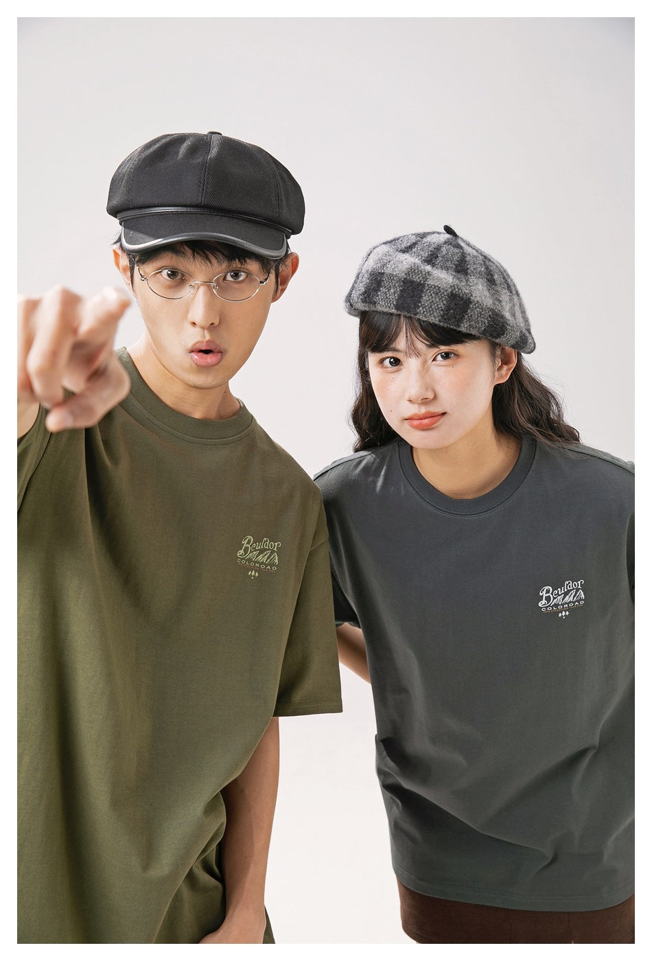 Close view of models wearing olive and charcoal T-shirts with small white chest prints.