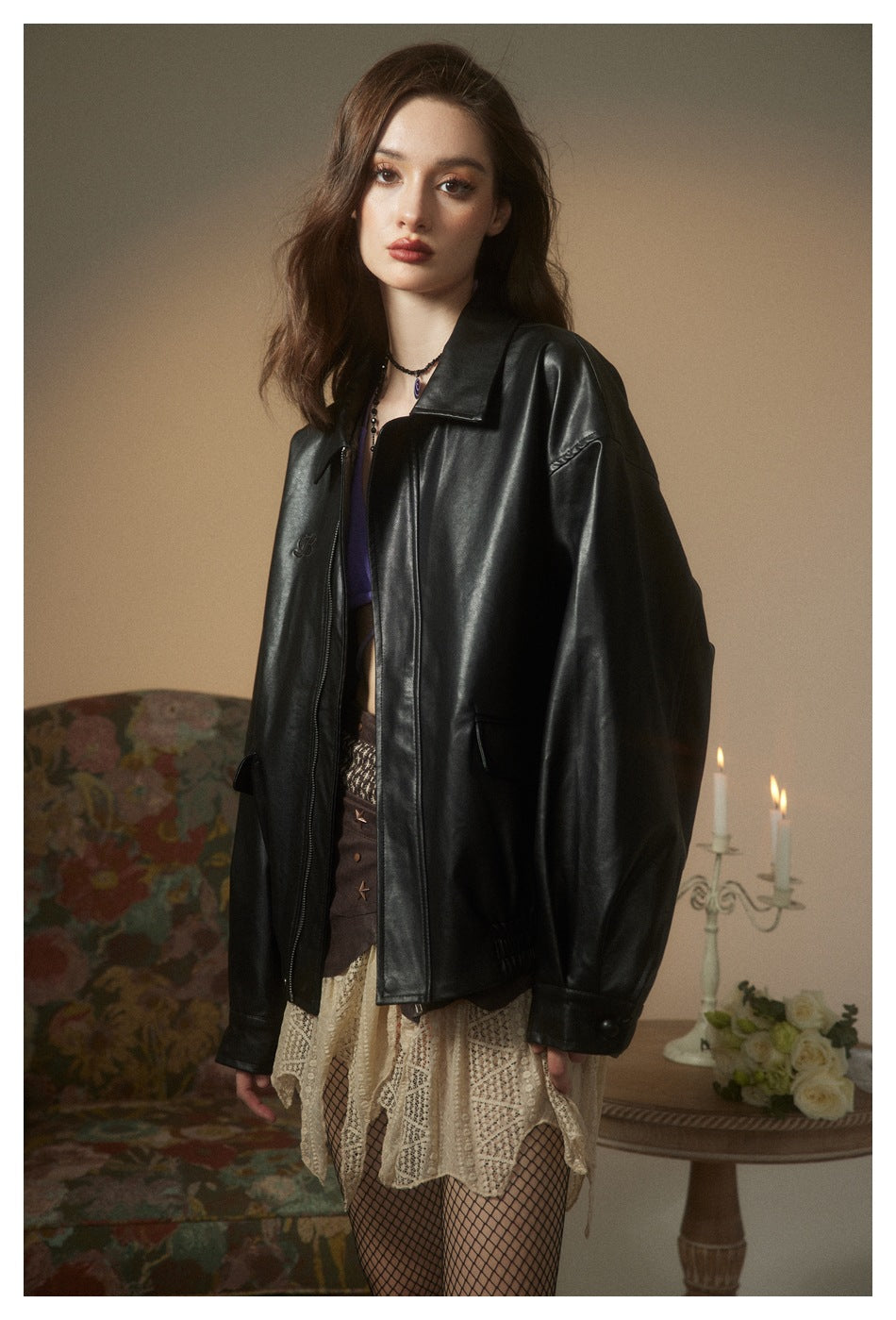 Model wearing a glossy black oversized jacket with a pointed collar, front zipper, and flap pockets.