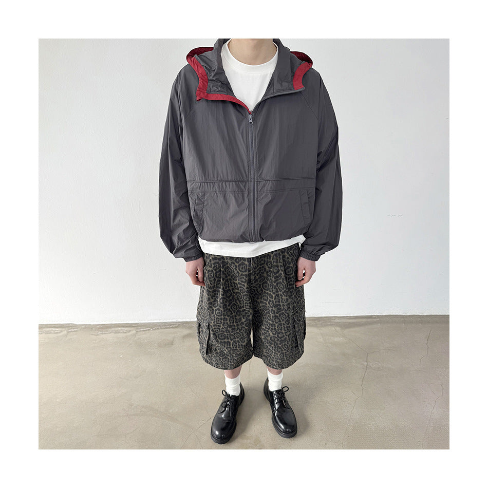Person wearing a gray hooded zip jacket with red hood lining, white tee, leopard-print cargo shorts and black shoes