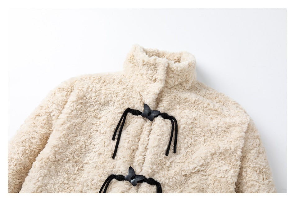 Close view of the ivory plush coat's upper front, high collar, and black toggle closure.