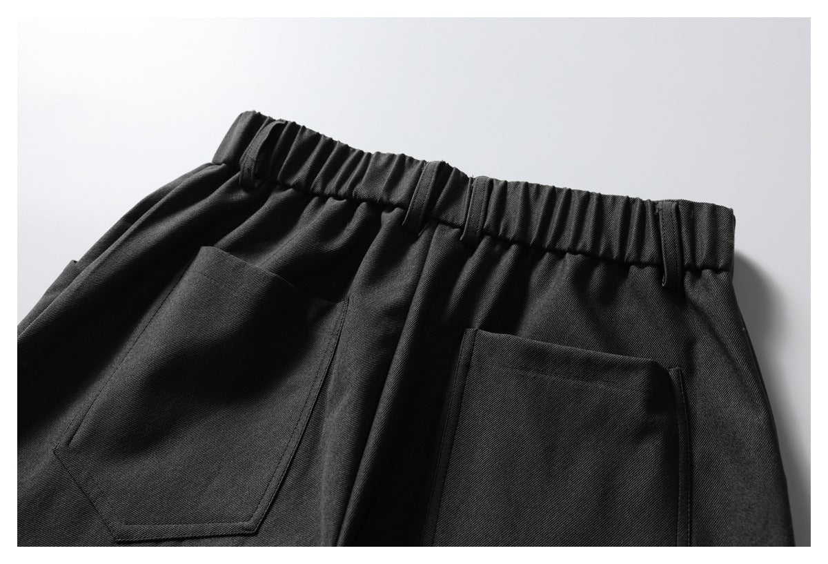 Cropped rear view of dark trousers with a gathered waistband and two large patch pockets.