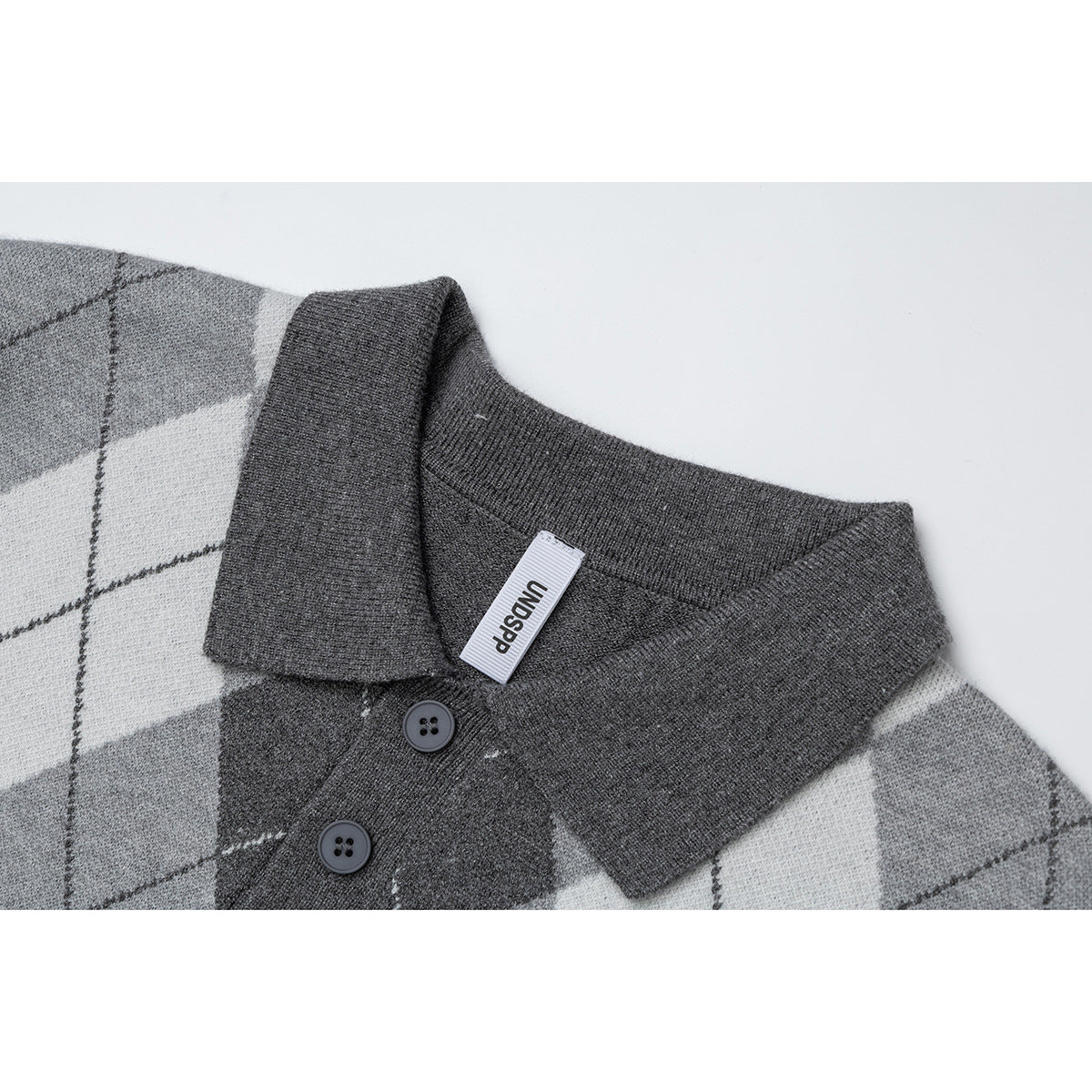 Close-up of a gray argyle knit polo collar with two dark buttons and a small white neck label.