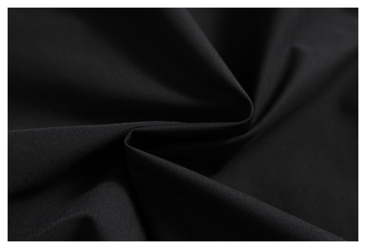 Close-up of black fabric arranged in soft folds, showing a fine diagonal weave.