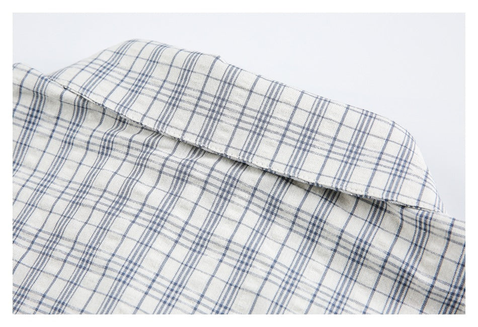 Close-up of a cream shirt collar with a blue-gray plaid pattern and visible stitching.