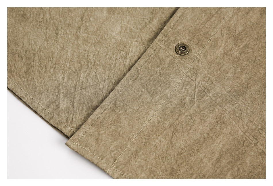 Close-up of taupe-brown mottled garment fabric, stitched edge and a round metal button.