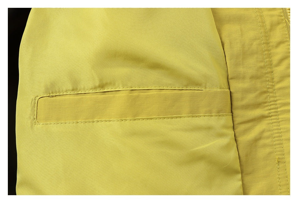 Close-up of a yellow garment showing a stitched rectangular pocket and adjacent seam.