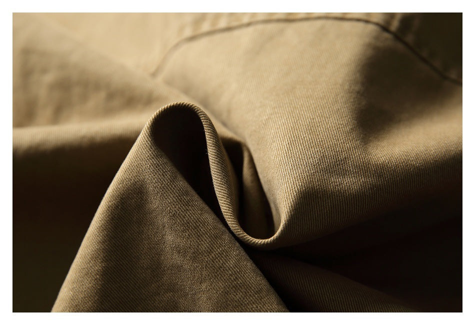 Macro view of tan-brown garment fabric folded to show its fine diagonal weave and stitched edge.