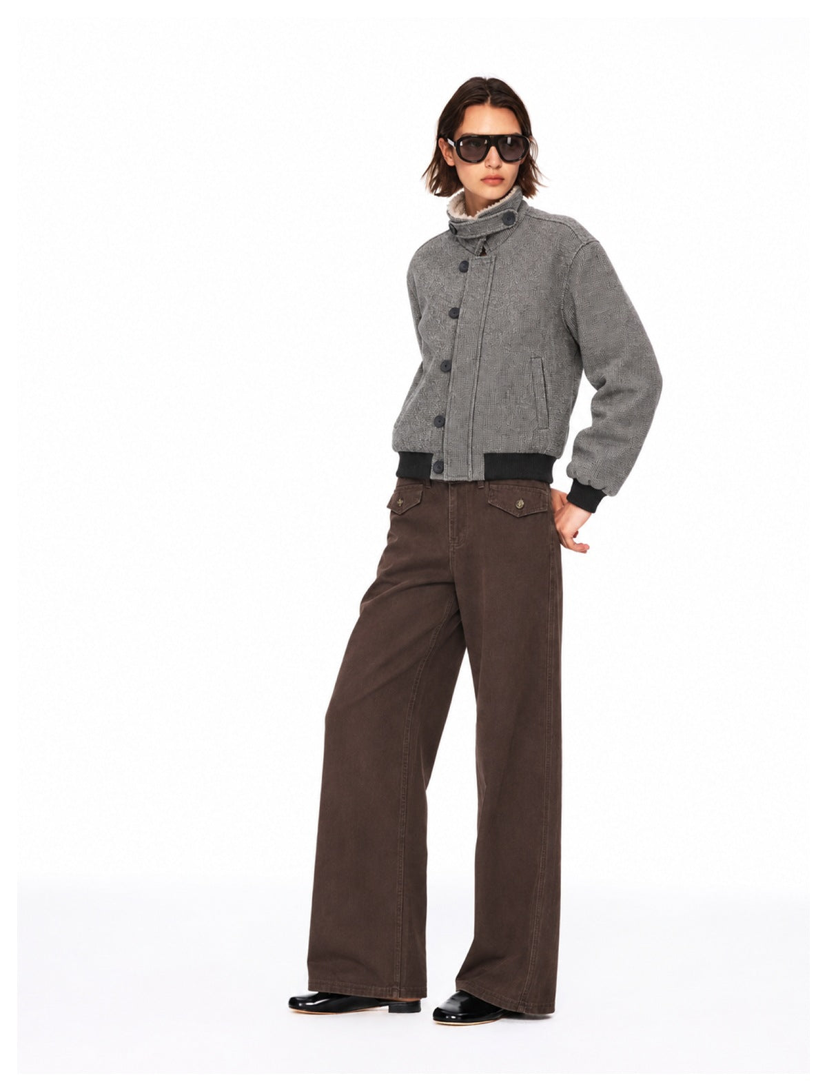 Model wearing brown wide-leg pants with button-flap pockets and a gray bomber-style jacket