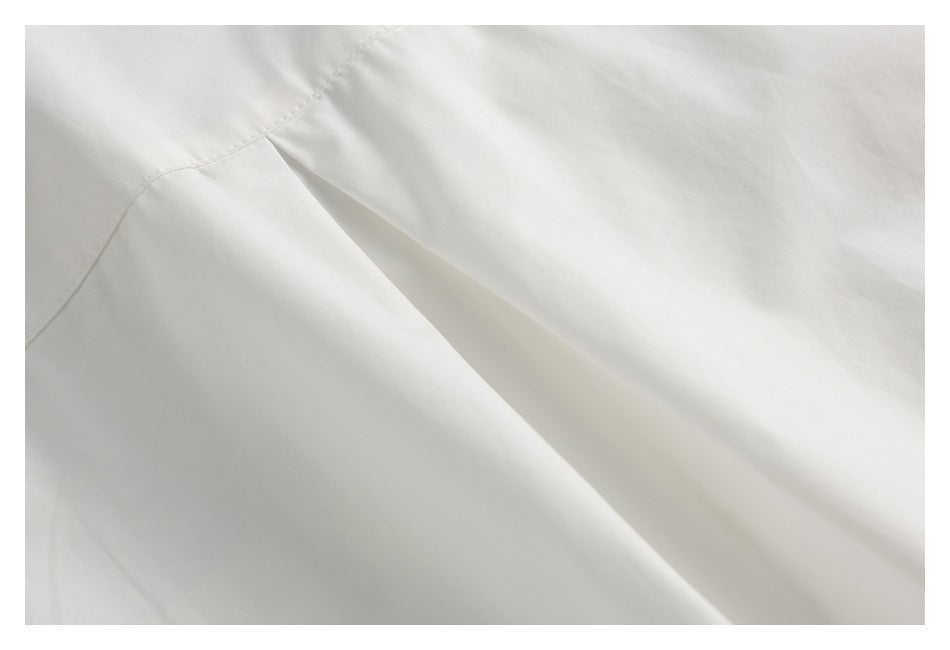 Close-up of white garment fabric with a curved stitched seam and folded panel.