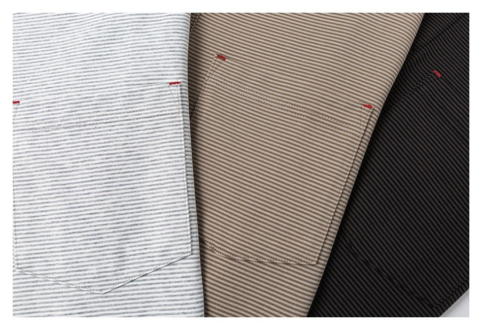Close-up of striped polo chest pockets in light gray, taupe, and black, each with a small red stitch detail.
