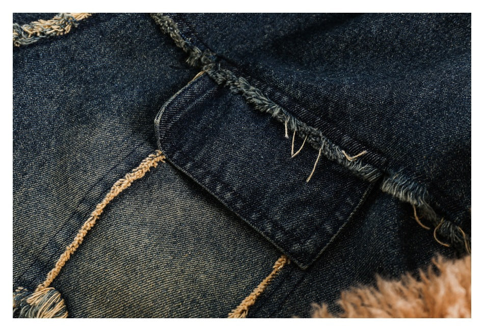 Close-up of a dark denim jacket panel with a curved pocket and frayed tan seams.