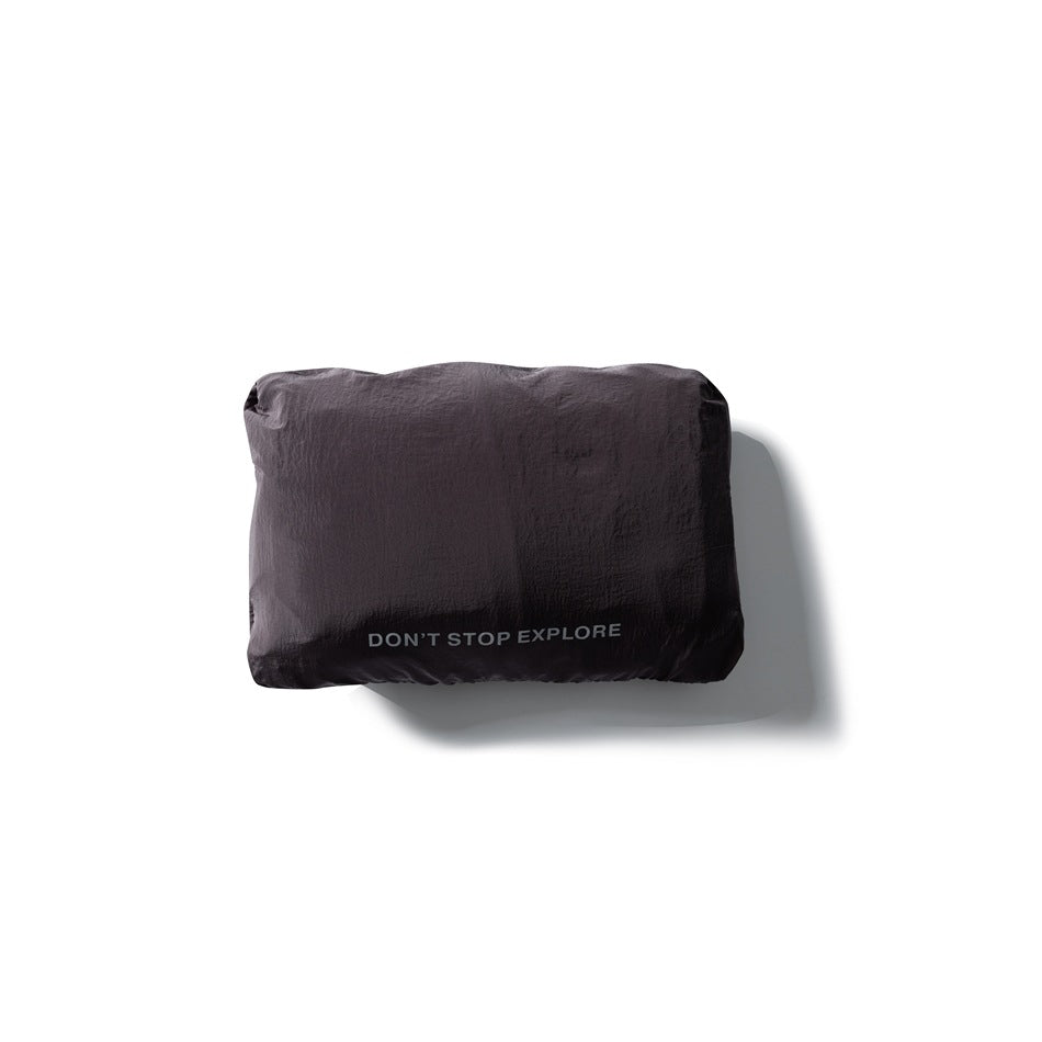 Dark garment folded into a compact rectangular pouch printed with “DON’T STOP EXPLORE.”