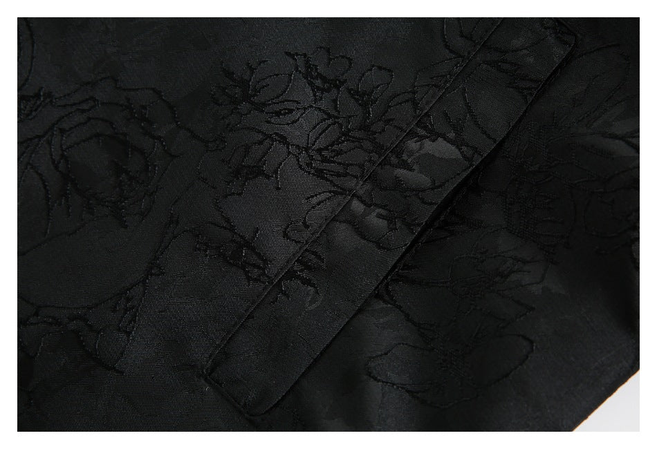 Close-up of black floral-patterned fabric with a wide diagonal seam or garment trim.