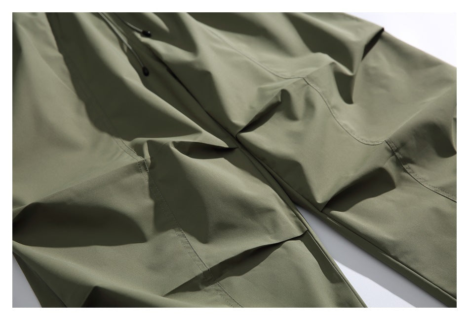 Close-up of olive-green garment fabric with black buttons, stitched seams and a curved pocket.
