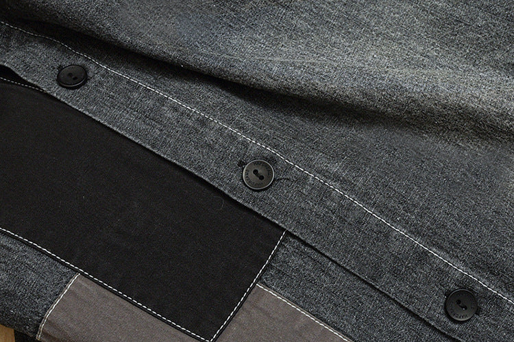 Close-up of gray and black color-block garment panels with black buttons and white contrast stitching.