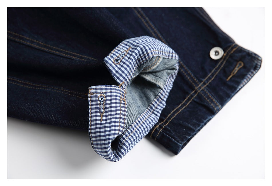 Close-up of a turned-back dark denim cuff showing blue-and-white gingham lining and the gray underside.
