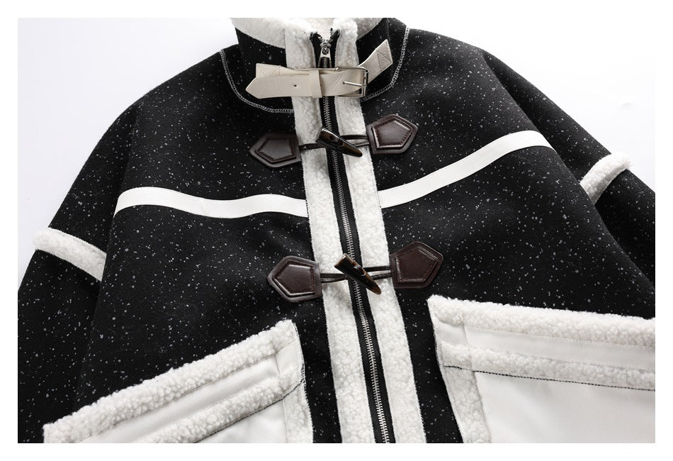 Partial front view of a black flecked coat with cream trim, toggle closures, a front zipper and large pale-trimmed pockets.