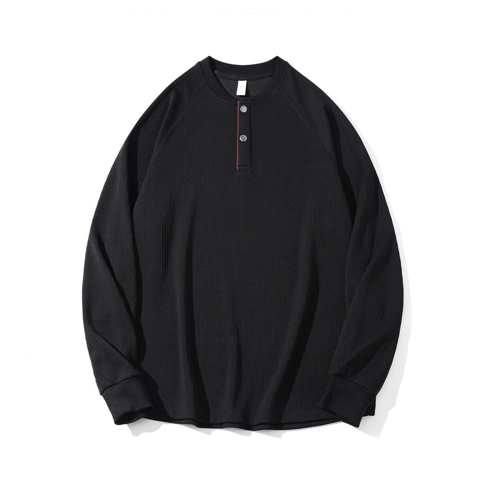 Black ribbed long-sleeve henley top with two snaps and burgundy placket piping, flat lay