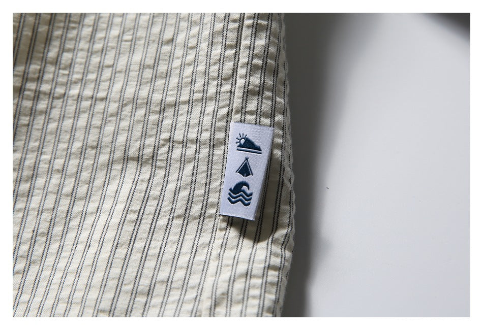 Close-up of a small sewn tab with outdoor pictograms on the striped shirt.