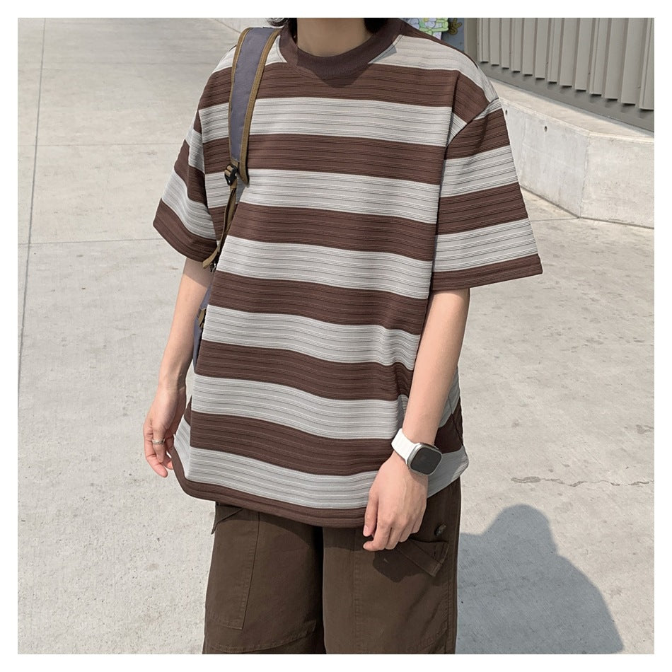 Close view of a person wearing an oversized brown and light gray horizontally striped T-shirt.