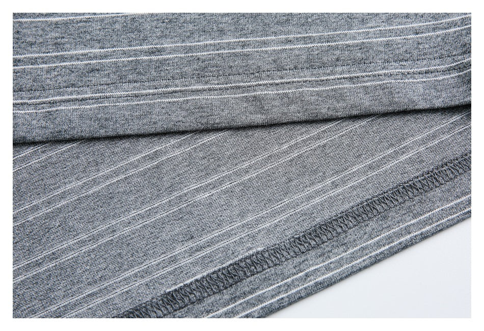 Close-up of gray heathered fabric with thin white stripes and an overlocked hem seam.
