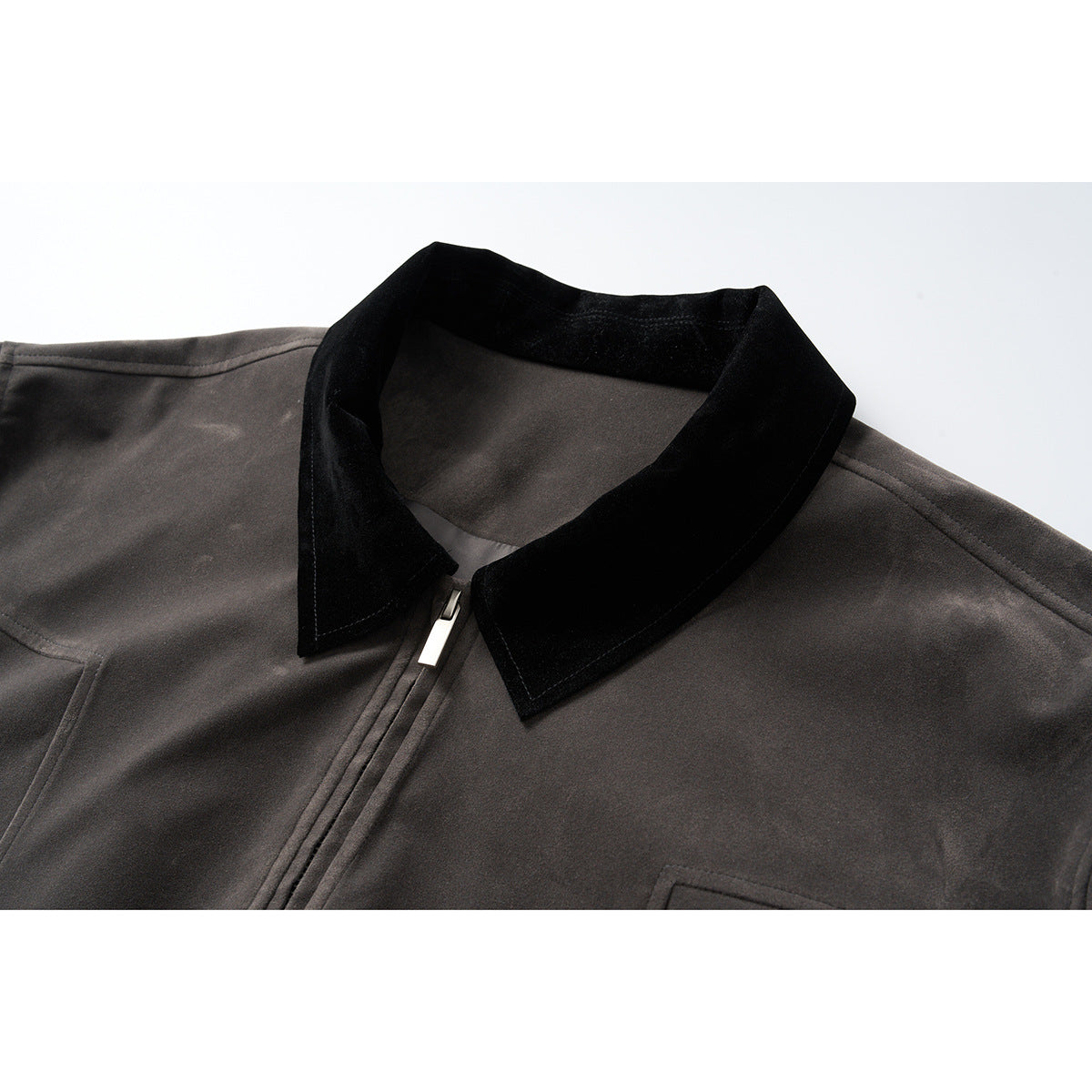 Close-up of a charcoal jacket with a black pointed collar and silver front zipper.