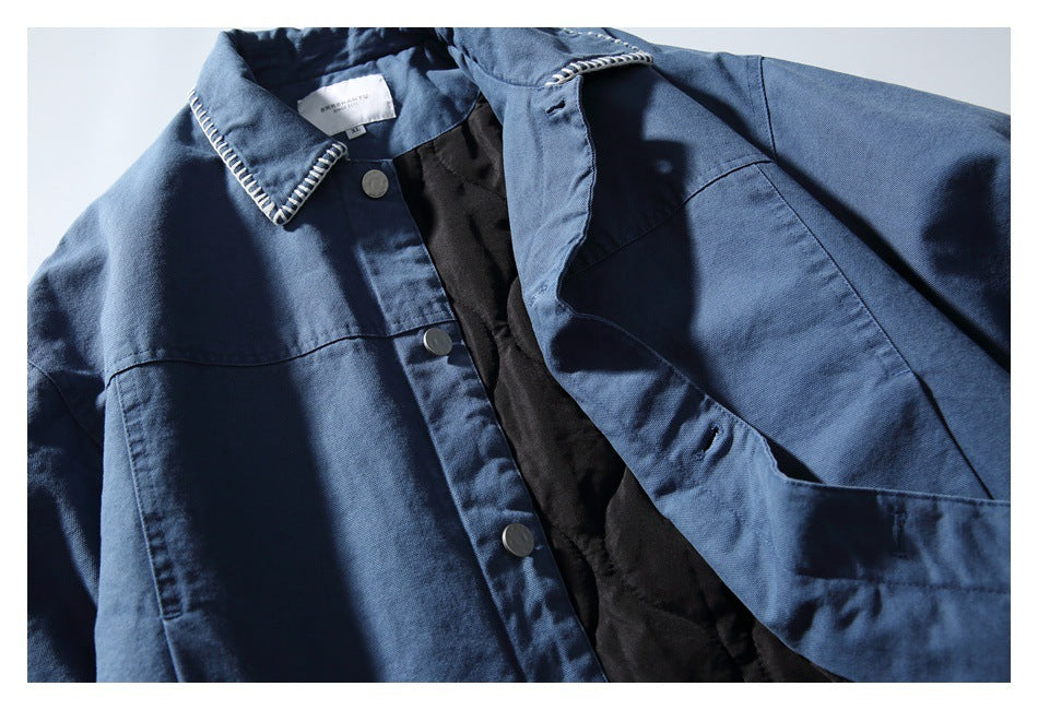 Blue jacket shown open from the front, with a pointed contrast-stitched collar, metal buttons, and black lining.