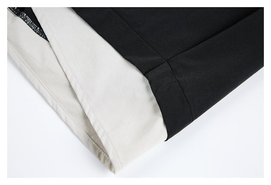 Close-up of a black trouser leg with a light cream-colored panel near the hem.