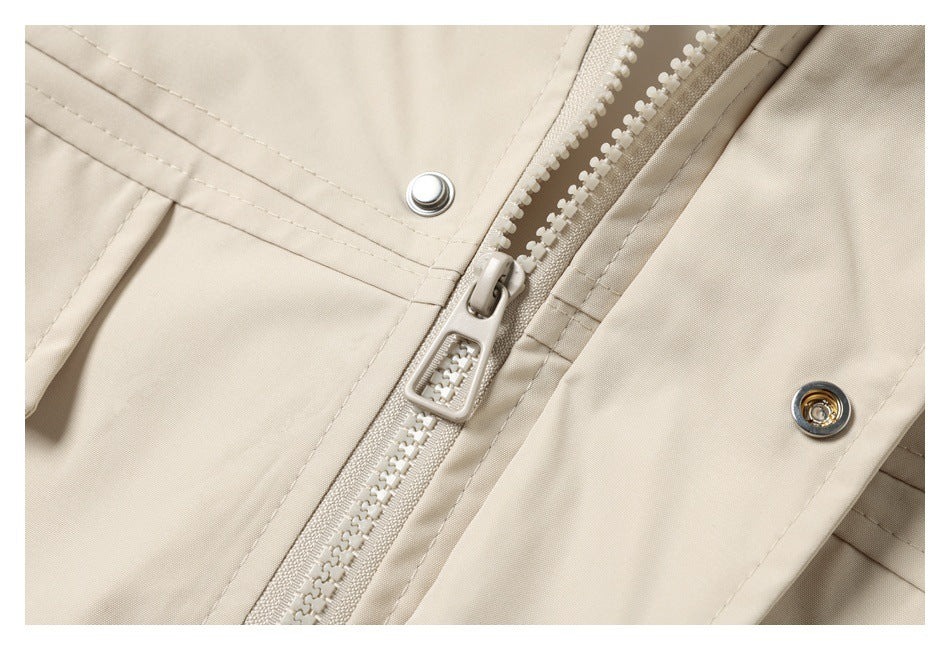 Close-up of a cream jacket's chunky front zipper, snap fasteners, and stitched seams.