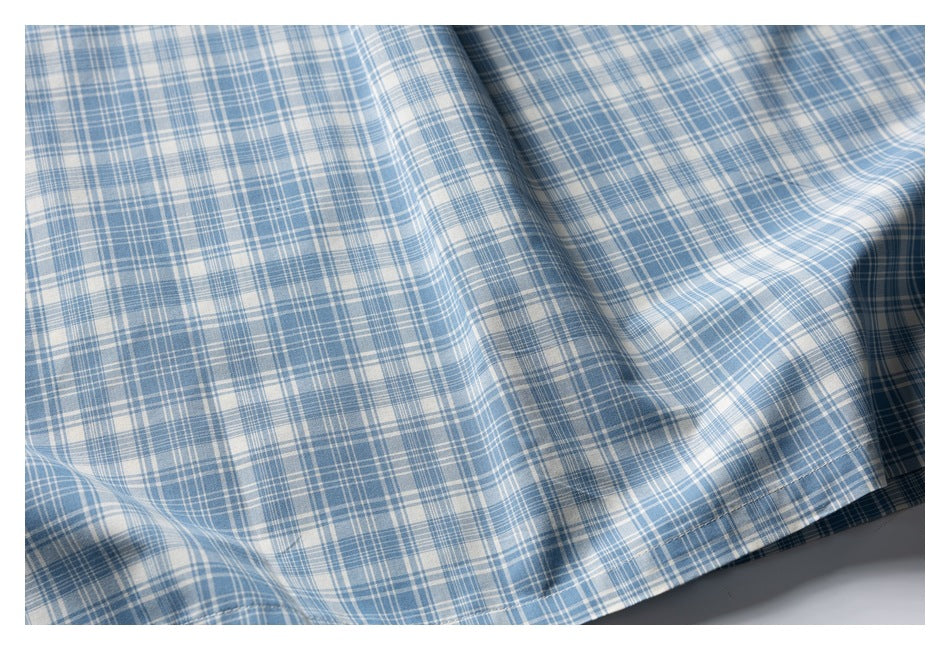 Close-up of the blue-and-white plaid shirt's fabric and stitched bottom hem.