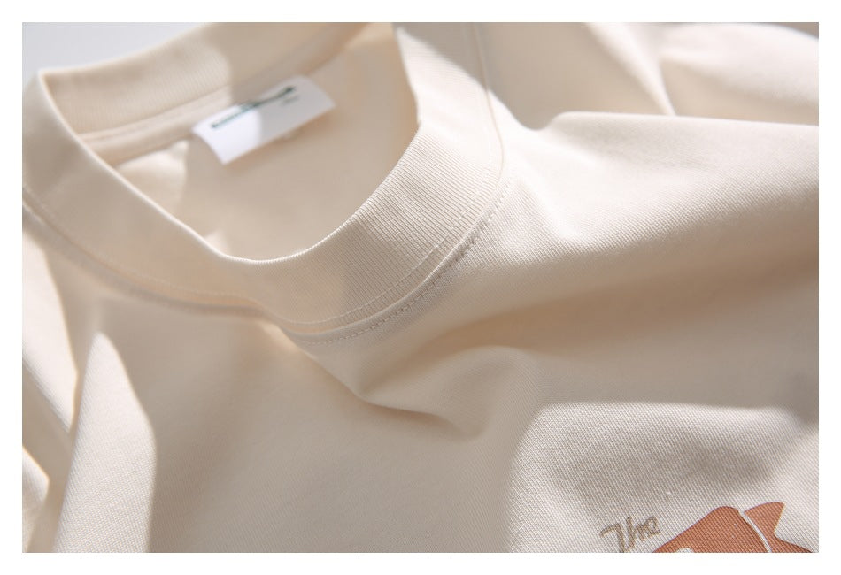 Close-up of the cream T-shirt’s ribbed crew neckline and shoulder seam.