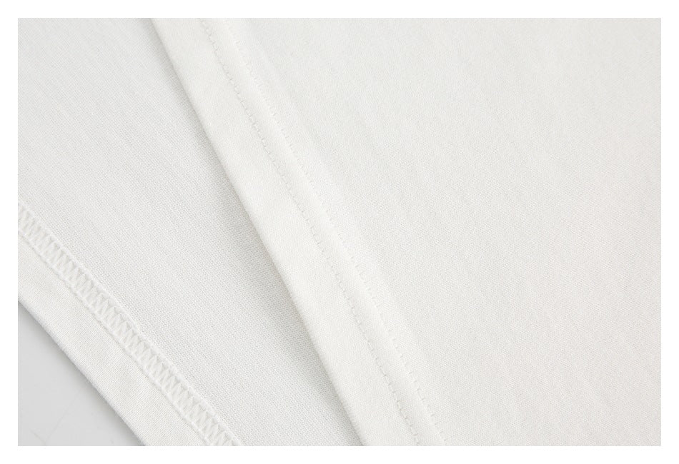 Close-up of white garment fabric showing a stitched seam and an overlocked edge.
